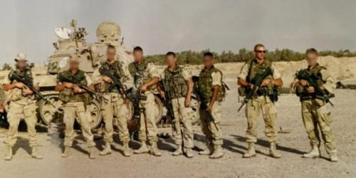 Mariniers staan naast elkaar met een tank op de achtergrond.